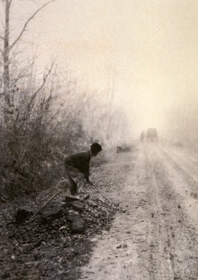A Country Road Wrapped in Morning Mists with a Man Splitting Stones in the Foreground by Unbekannter Künstler