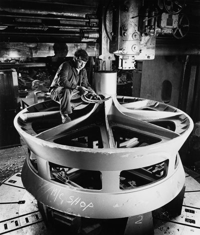 A fitter on top of a large cast item uses vertical boring machine by Unbekannt