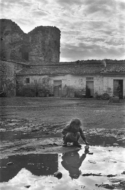 Young girl playing with a paper boat in a puddle surrounded by mud, Venosa, Basilicata, Italy by Unbekannt