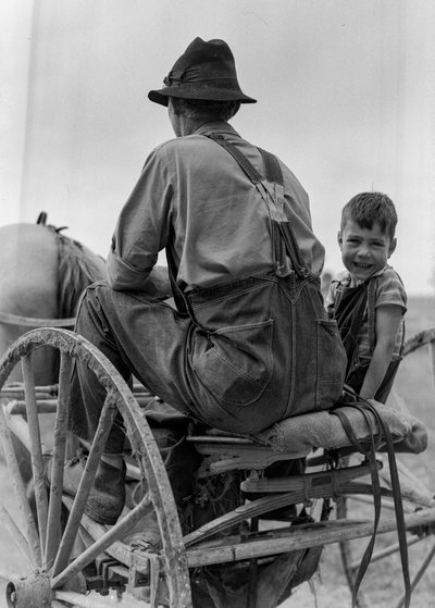 Farmer and smiling boy ride on the seat of a horse-drawn buggy in West Virginia by Volkmar Wentzel