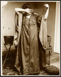 Female Model Standing with One Hand Over Her Face, Holding an Orb in the Other