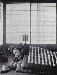 Girl asleep between wadded quilts with a wooden pillow