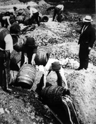 A US Federal Agent oversees the destruction of beer kegs during the American Prohibition era (1920-33)