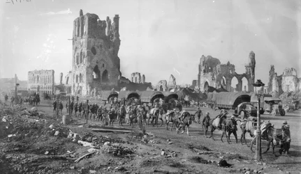 An unidentified Australian Machine Gun section with packed horses passing the ruins of the Cloth Hall. Note several motor lorries parked in the background, 19 October 1917