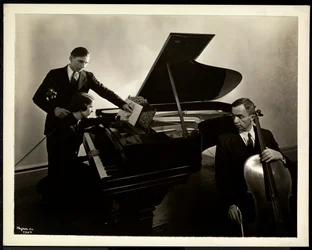 Blind woman, Miss Harding, at the piano instructing two blind men on the violin and cello, 1936