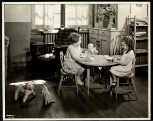 Two blind visually impaired girls eating at a small table with doll at the New York Association for the Blind, 111 East 59th Street, New York, 1933