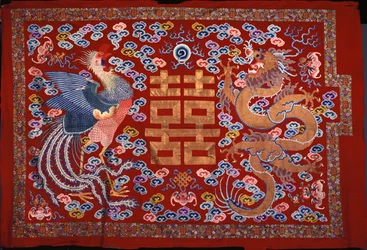 A Chinese Hanging of Red Wool with a Central Character in Gilt Thread Flanked by a Phoenix and a Dragon