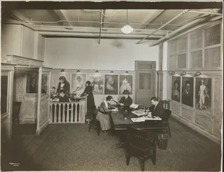 Main Office/Reception Room at the Mutual Film Co with Secretary at Desk, People at a Table Reading, and Portraits on Wall, New York