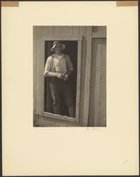 Man in a Straw Hat Standing in Doorway of a Barn Holding a Tobacco Pouch