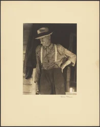 Mustached Old Man with Straw Hat and Suspenders Standing in Doorway