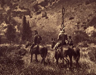 In Black Canon. The Apsaroke, without being exclusively mountain dwellers, always loved the hills, preferring monotonous meadows... the shade of the forests and the clear rivers. The photo illustrates the custom of wearing a headband behind the head or han