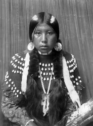 Kalispel Indian woman, white stripes painted on hair, shell disk earrings, wearing blanket dress decorated with elks