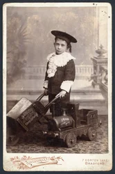 Boy with a toy train and wheelbarrow