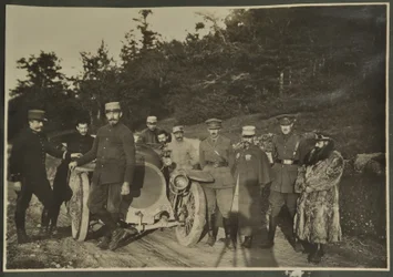 William Lawrence Bragg and Harold Roper as part of a group with a motorcar on a mountain road, Vosges, 1915