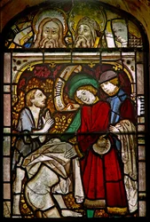 A panel in the east window depicting the Works of Mercy: clothing the naked: also some fine reset heads