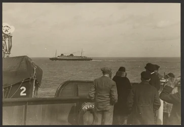 Group of People on the Deck of a Ship Watching Another Ship Sailing Past in the Distance