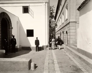 Men in uniform accompanying an elegantly dressed woman towards the church of the farm of Lo Zucco, Sicily