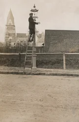 Man up a ladder fixing a street lamp