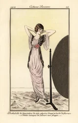 Woman in lilac muslin silk dress with black velvet vest looking at herself in a mirror. Deshabille of lilac muslin silk, draped and fur-trimmed, small jacket of patterned black velvet. Handcoloured pochoir etching after an illustration