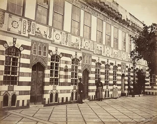 The courtyard of a Jewish house in Stambouli, Syria, Three domestics are shown near the walls of the building