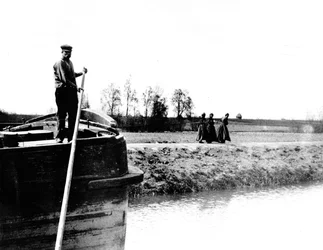Barge being towed on a canal by three women