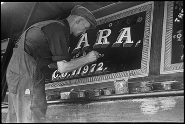Frank Jones painting the name panel on a barge, 20th century