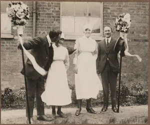 Two men holding tutti poles with two women during the Hocktide Festival in Hungerford