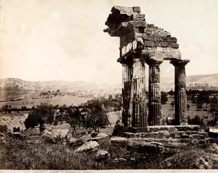 View of the remaining four columns supporting an entablature of the Temple of Castor and Pollux in the Valle dei Templi, Agrigento. A panorama of the city is visible in the background