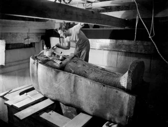 Discovery of the tomb of Pharaoh Tutankhamun in the Valley of the Kings (Egypt): in the burial chamber, Howard Carter working on the lid of the second coffin, October 1925, photo by Harry Burton (p1568)