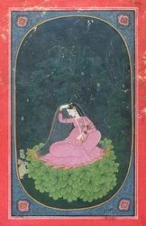 Woman seated on a bed of leaves in a forest