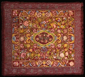 An Italian table carpet embroidered in brightly coloured silks with a central medallion of roses within a field of lilies and larger flowers