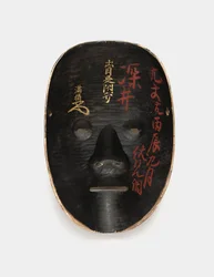 Reverse of a wood mask covered with sumi, lacquered with inscriptions in red