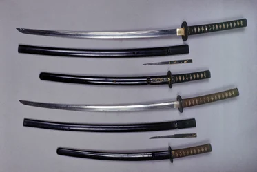 Top: a katana, Japanese sword and its sheath, wakizashi, Japanese short sword in its sheath, small Kokatawa dagger stows in the same scabbard. All three are from the 18th century. The lower ones are from the 17th century