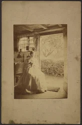 Woman in long striped dress seated inside room