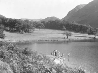 A family on the edge of the lake fishing and looking in the water
