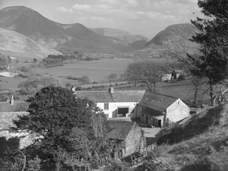 A view of a farm in the foreground with a lake and hills in the background