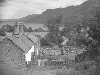 Farm buildings with sheep in farmyard and Ullswater in background