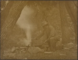 Man Cooking on Camping Fire in Woods