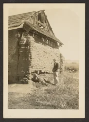 Two Men Near Crumbling Cottage