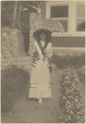 Woman Standing in Front Yard with Camera and Plaid Umbrella