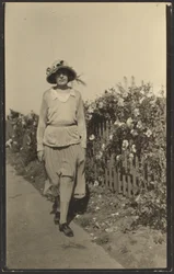 Woman Walking Along Fence with Flowers