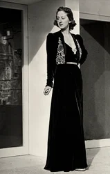 Model wears long evening dress of dark velvet with embroidered decoration, created by the Italian couture house 