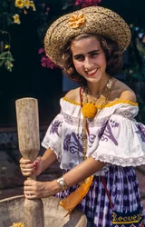 Woman in straw hat of Panama grinding with a traditional mortar and pestle