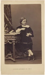 Unidentified Little Girl Standing, Elbow on Top of a Closed Book on a Table