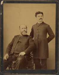 Unidentified Bearded Man Seated with Unidentified Man with Moustache Standing