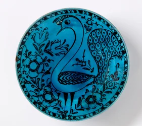 A 19th-century Persian pottery dish depicting a peacock on a turquoise background