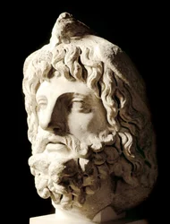 Roman art: bearded head covered by a dead bird of Sarapis or Serapis, Greek-Egyptian god of Death. Marble sculpture from Carthage. Paris, Musee du Louvre