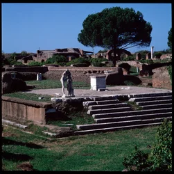 Roman art: view of the ruins of the temple of Hercules and statue of Gaius Cartilius Popplicola, citizen of Ostia