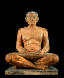 Egyptian Antiquities: The Scribe Squatting. Statue in limestone, albaster and rock crystal. Louvre Museum, Paris