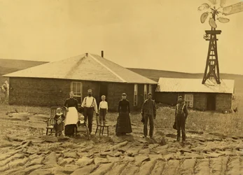 Family of Homesteaders, Outside of Their Sod House with a Windmill on the Roof of the Adjoining Building in Custer County, Nebraska